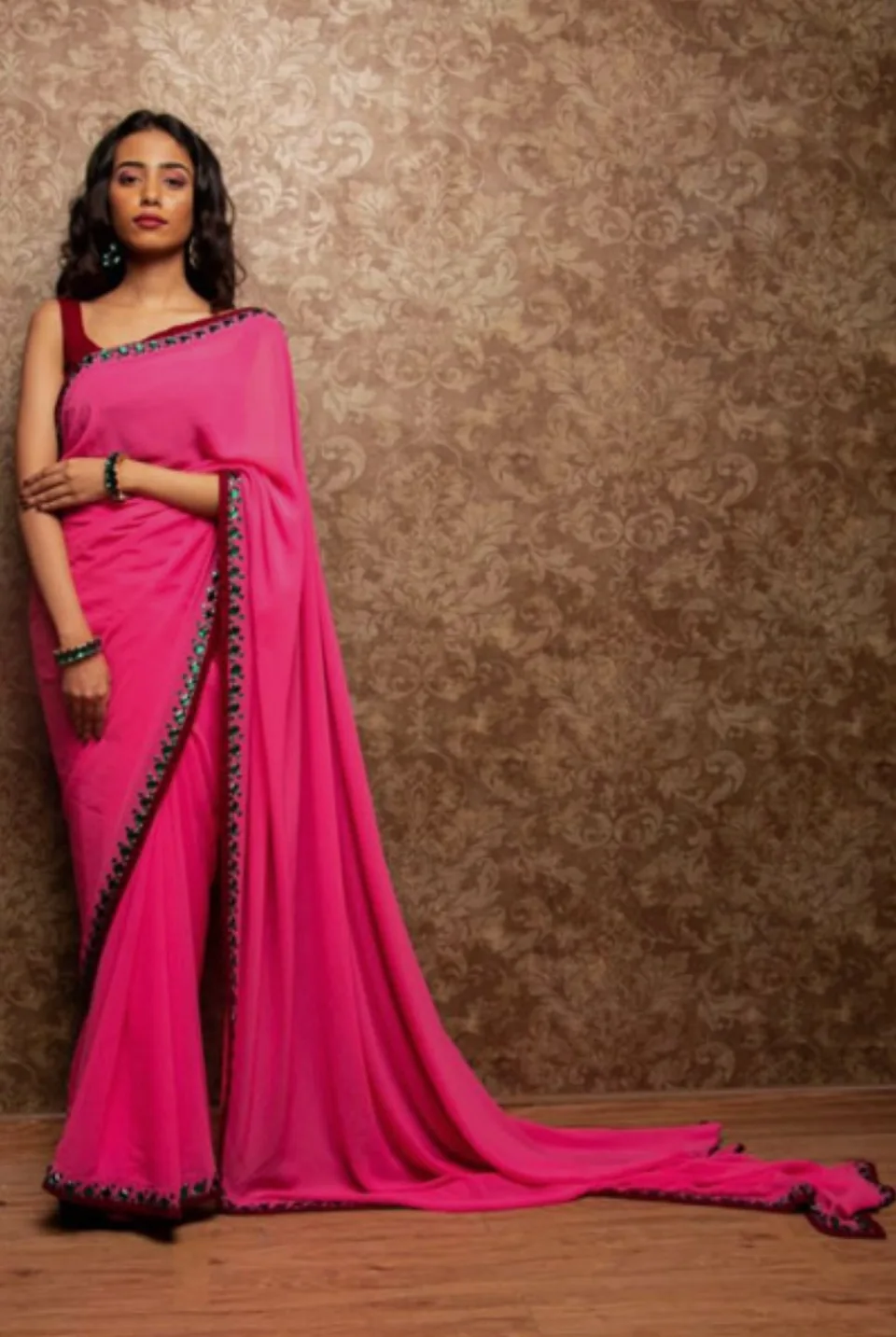 Full-length view of the rani pink saree, its train spread across a wooden floor against damask wallpaper.